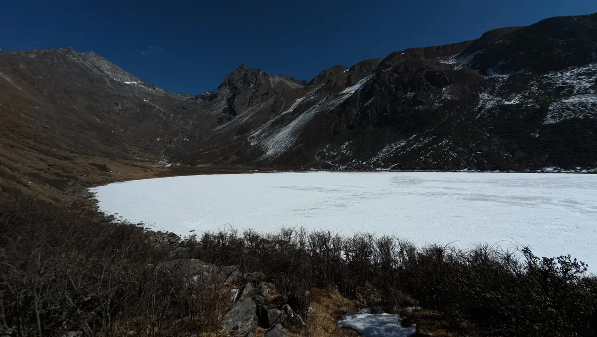 Frozen alpine lake surrounded by steep mountain slopes